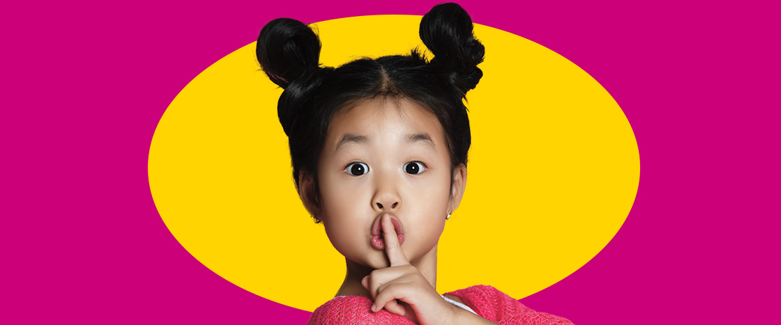 Image of a kid with finger covering mouth to communicate being quiet